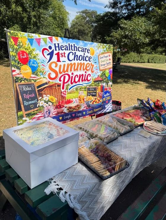 Healthcare 1st Choice Summer Picnic banner with a picnic table of food in the park